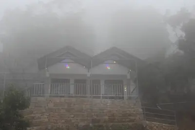 a house in the fog in front of a house at Amber Mount Resorts in Kanthalloor