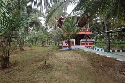 a small red building with palm trees in front of it at Coconut Sooru,Managed By Triora Escapes in Maddūr