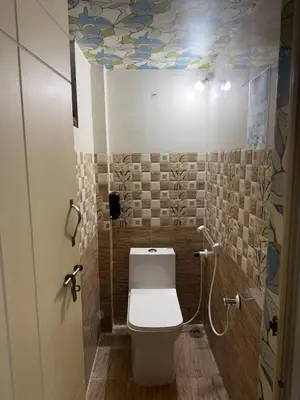 a bathroom with a toilet and a ceiling with flowers at Coconut Sooru,Managed By Triora Escapes in Maddūr