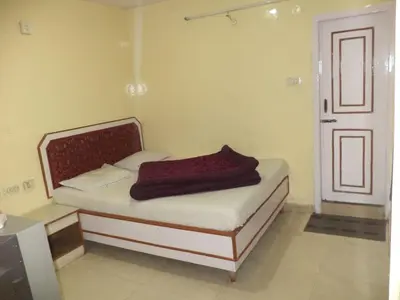 a bedroom with a bed with a red blanket on it at BKC Lakshmi Cottage in Ooty