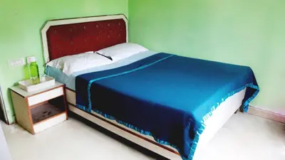 a bedroom with a blue bed with a red headboard at BKC Lakshmi Cottage in Ooty