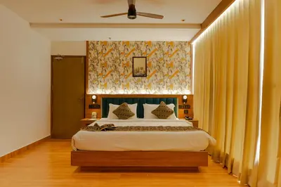 a bedroom with a large bed with yellow curtains at Hotel Sky International in Kizhake Chālakudi