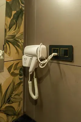 a white phone is hanging on a wall at Hotel Sky International in Kizhake Chālakudi