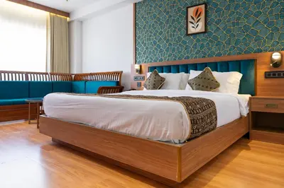 a bedroom with a large bed with a blue wall at Hotel Sky International in Kizhake Chālakudi
