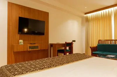 a hotel room with a bed and a flat screen tv at Hotel Sky International in Kizhake Chālakudi