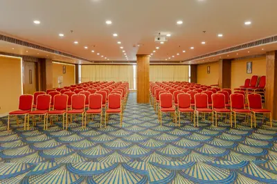 a conference room with red chairs and a carpet at Hotel Sky International in Kizhake Chālakudi
