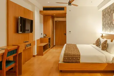 a bedroom with a bed and a desk and a television at Hotel Sky International in Kizhake Chālakudi