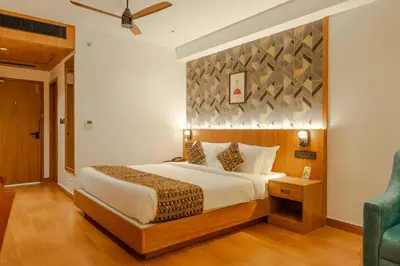 a bedroom with a large bed and a blue chair at Hotel Sky International in Kizhake Chālakudi