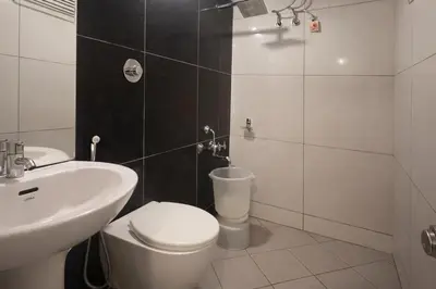 a bathroom with a white toilet and a sink at Rooms By DeVerveil in Mysore