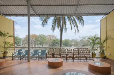 a patio with chairs and tables and a view of the water at Rooms By DeVerveil in Mysore