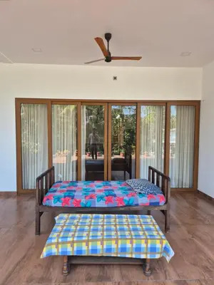 two beds in a room with sliding glass doors at Prabhu Villla Upper Deck in Perumbavoor
