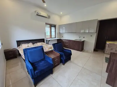 a bedroom with a bed and two blue chairs at Prabhu Villla Upper Deck in Perumbavoor