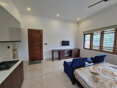 a kitchen with a bed and a desk in a room at Prabhu Villla Upper Deck in Perumbavoor