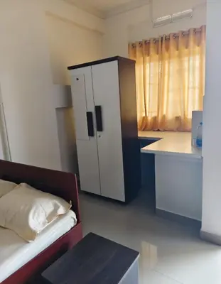 a room with a bed and a kitchen with a cabinet at Darshanam Inn in Guruvāyūr