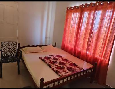 a bedroom with a bed with a red curtain at Darshanam Inn in Guruvāyūr