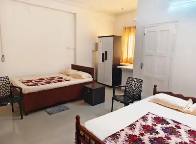 a bedroom with two beds and two chairs and a cabinet at Darshanam Inn in Guruvāyūr