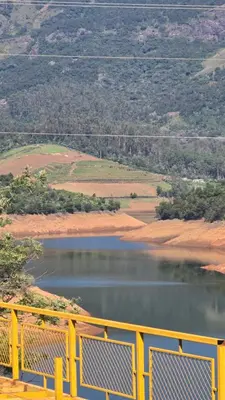 a view of a lake with a yellow fence at Silver lake nature escape in Ooty