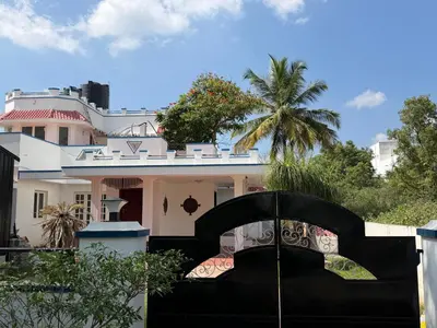 a house with a black gate and a palm tree at Didan Stays in Coimbatore