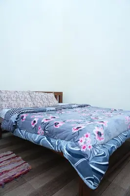 a bed with a blue blanket with flowers on it at Sparrow valley in Coonoor