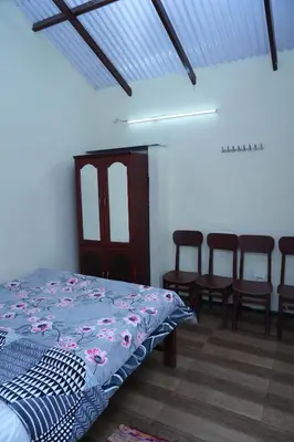 a bedroom with a bed with chairs and a table at Sparrow valley in Coonoor
