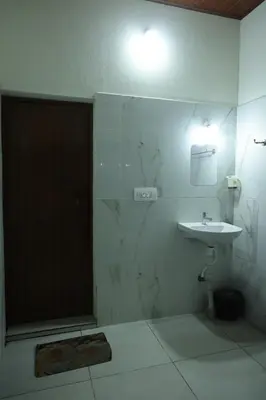 a bathroom with a shower with a sink and a mirror at Coorg Backwaters in Suntikoppa