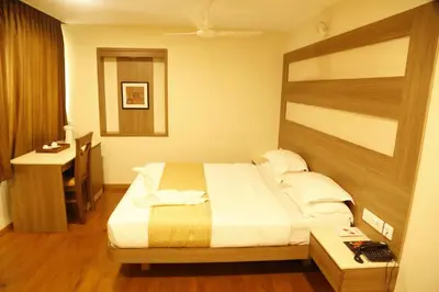 a bedroom with a bed and a desk in it at HOTEL GRAND PLAZzA in Coimbatore