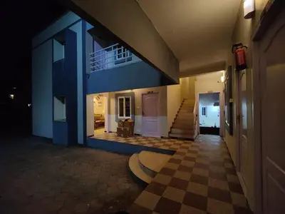 a hallway with a blue building with a checkered floor at Posh Holidays in Ooty