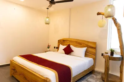 a bedroom with a bed with white sheets and red pillows at Coconest Premium Deluxe Rooms in Pollāchi