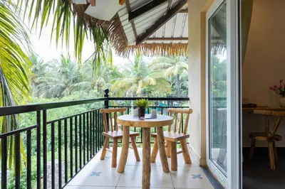 a dining room with a table and chairs on a balcony at Coconest Premium Deluxe Rooms in Pollāchi