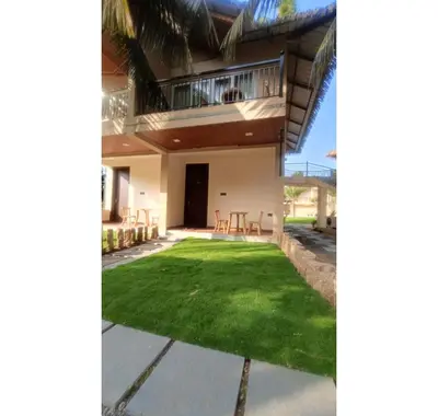 a house with a green lawn in front of it at Coconest Premium Deluxe Rooms in Pollāchi