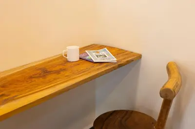 a wooden shelf with a cup and a newspaper on it at Coconest Premium Deluxe Rooms in Pollāchi