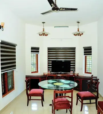 a living room with a table and chairs and a tv at White Haven in Angamali