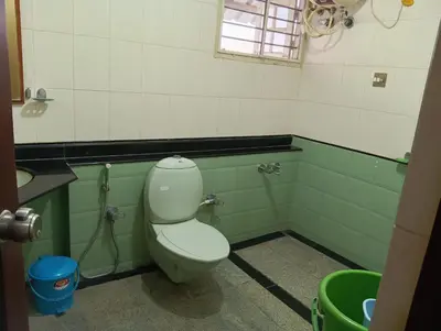 a bathroom with a toilet in a green and white room at MANTRAs in Mysore
