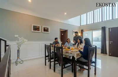 a group of people sitting around a dining room table at EKOSTAY - Echo Villa in Kodaikānāl