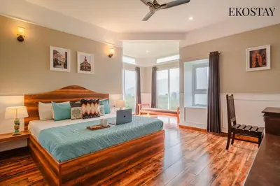a bedroom with a bed and a desk with a laptop at EKOSTAY - Helios Villa in Kodaikānāl