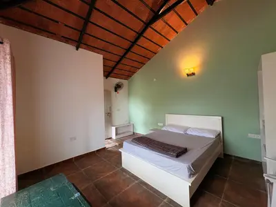 a bedroom with a white bed in a room at Paddy Creek Jungle Resort Coorg in Virajpet