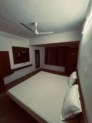 a bedroom with a large bed and a flat screen tv at hotel sri kaliappaa in Coimbatore
