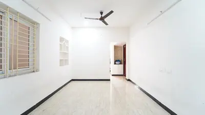 an empty room with white walls and a ceiling fan at H N Residency in Coimbatore