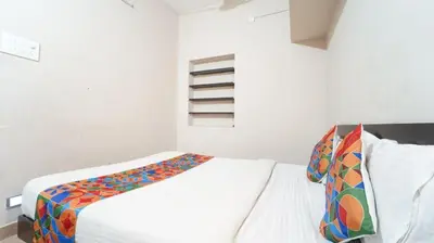 a white bedroom with a bed with a colorful blanket at H N Residency in Coimbatore