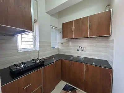 a kitchen with wooden cabinets and a sink at 1bhk Kalp Guruvayur 150m to temple in Trichūr
