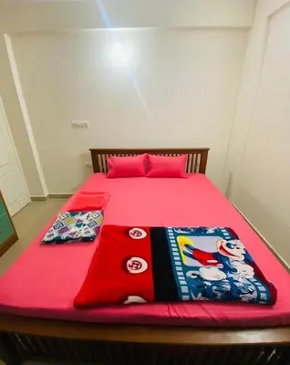 a bed with a red blanket and two pillows on it at Apartment in Guruvayur- Sooryamadhavam-only for families in Guruvāyūr
