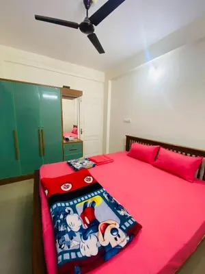 a bedroom with a pink bed with a red blanket at Apartment in Guruvayur- Sooryamadhavam-only for families in Guruvāyūr