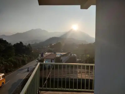 a view from the balcony of a house with the sun setting on a mountain at Vista Chembra Service Apartment 20B in Meppādi