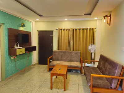 a living room with a couch and a table at Vista Chembra Service Apartment 20B in Meppādi