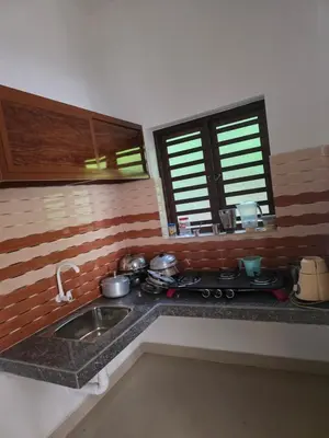 a kitchen with a sink and a stove and windows at Paithal haven in Paithalmala