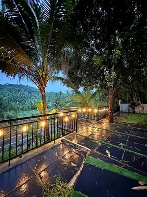 a garden with a fence and trees and lights at Bougainvilla in Kozhikode