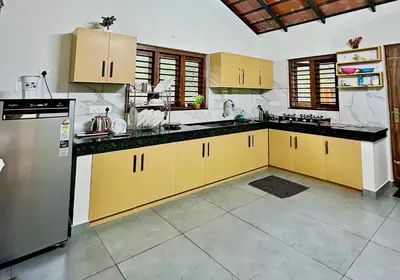 a kitchen with yellow cabinets and a stainless steel refrigerator at Bougainvilla in Kozhikode