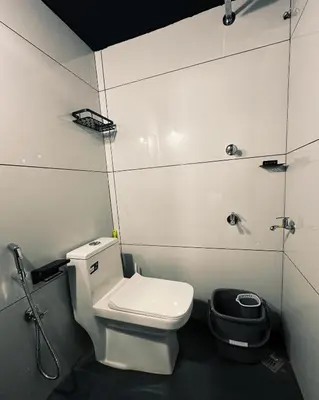 a bathroom with a white toilet and a shower at Ebb & Flow in Irimbranallūr