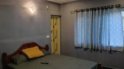 a bedroom with a bed with blue curtains at Msk indian Residency in Kodaikānāl