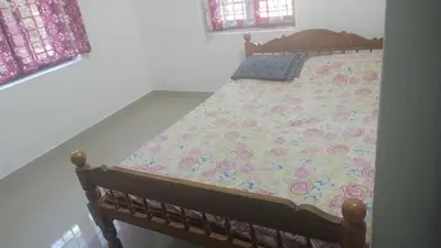 a bedroom with a bed with a floral comforter at Aswathy Bhavan in Vadakkāncheri